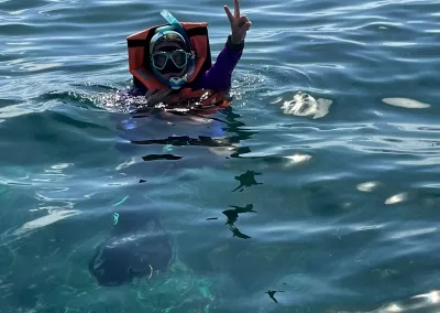 person making a peace sign while snorkeling in the ocean