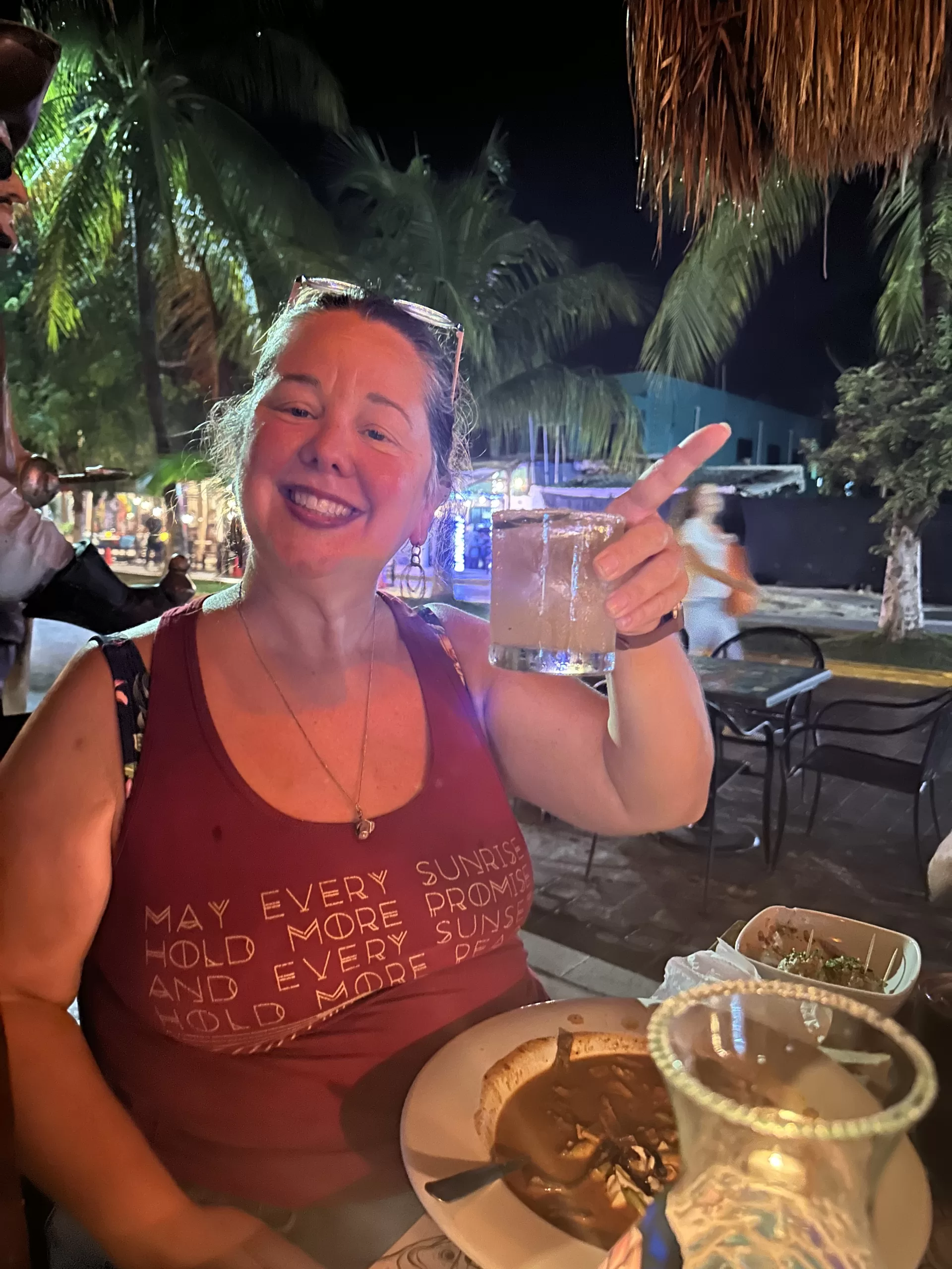 Bridget Espinosa holding a glass of alcohol, enjoying an evening at a restaurant in Puerto Morelos.