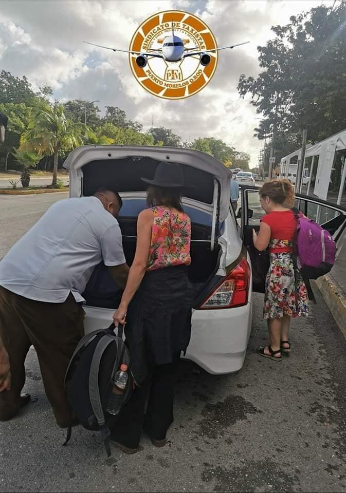 PM taxi airport shuttle with driver assisiting a passenger with her luggage.
