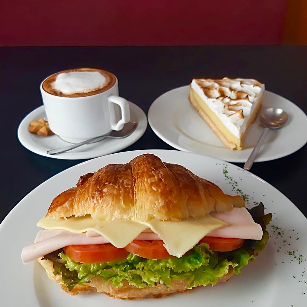 A delicious, gourmet lunch at Belleville including a croissant sandwich, a slice of lemon tart, and a latte.