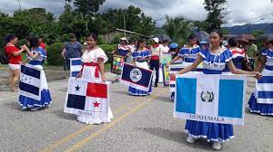 Parade for Central American Independence Day with children dressed in typical clothing and carrying flags from the countries of the region.