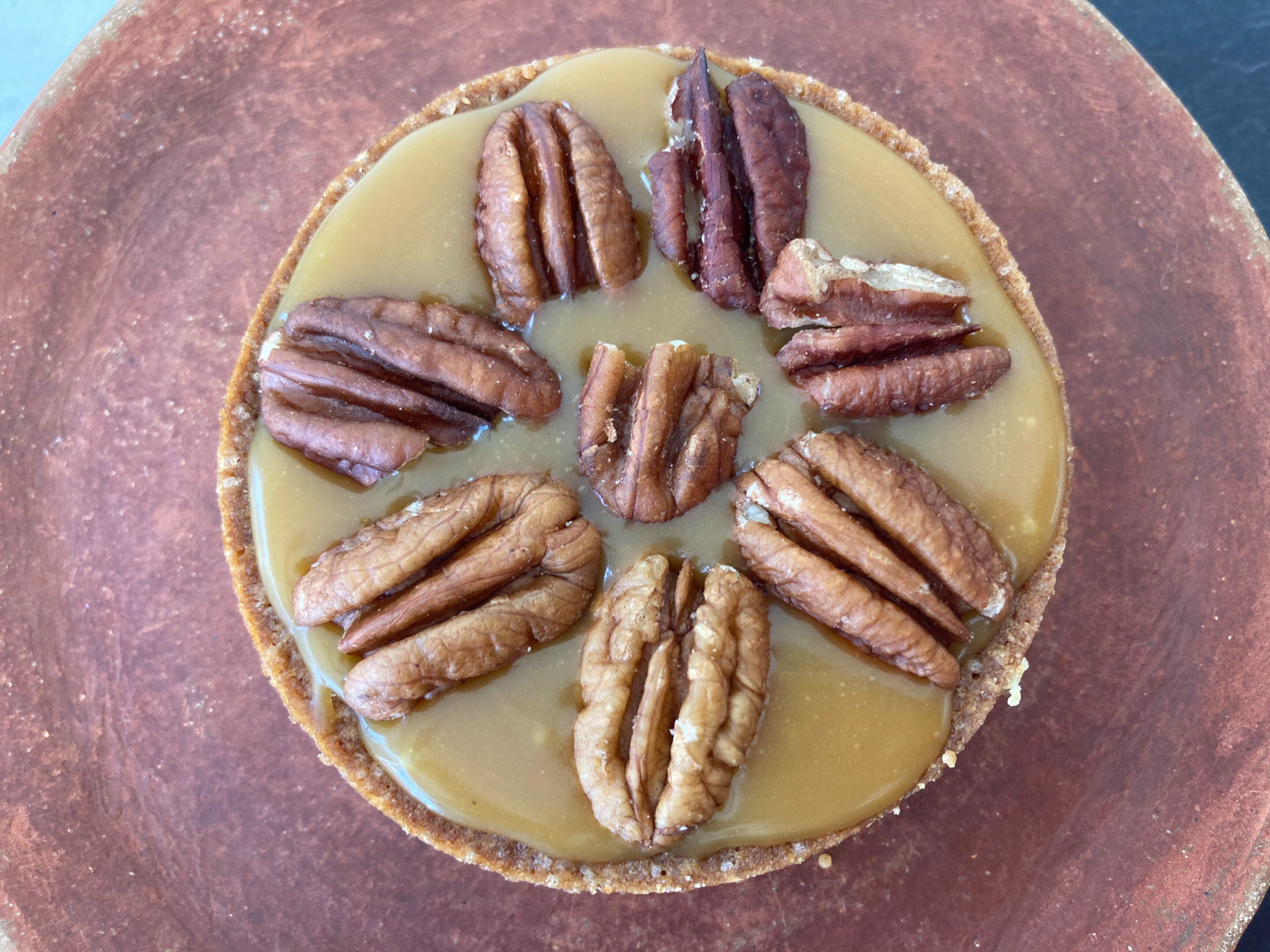 A lovely dessert from Belleville, topped with caramel and pecans, served on a artesanal clay plate.