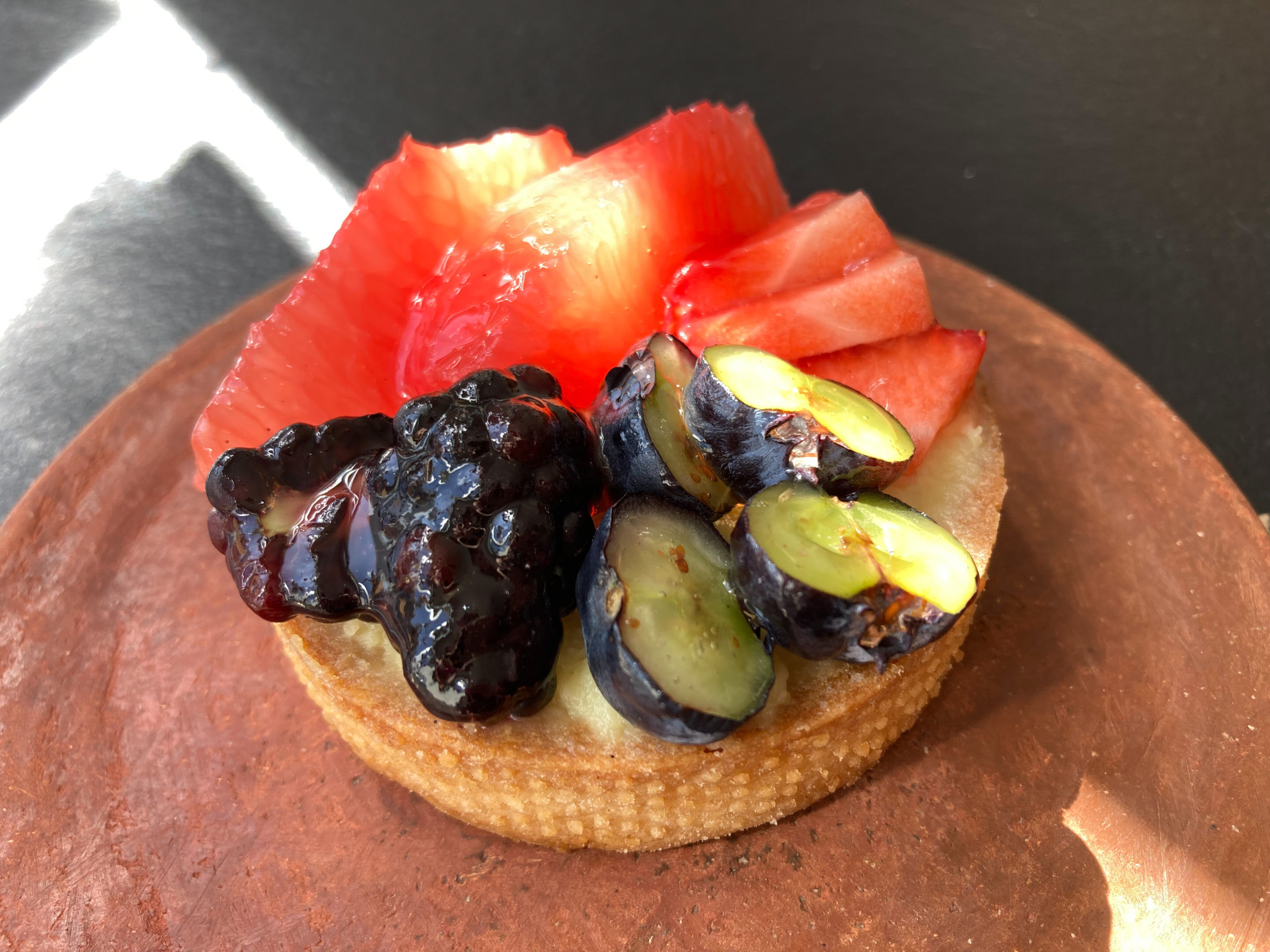 Image of Belleville's fruit tart, topped with a variety of fruits including black berries, blueberries, strawberries.