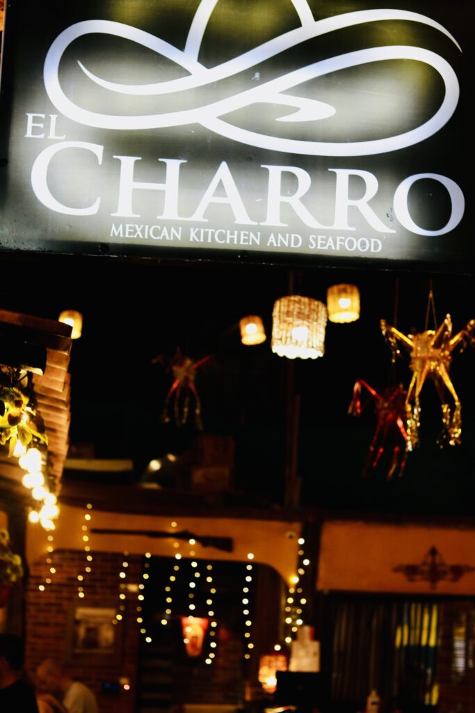 El Charro Mexican Restaurant logo against a backdrop of festive lights and colorful pinatas.