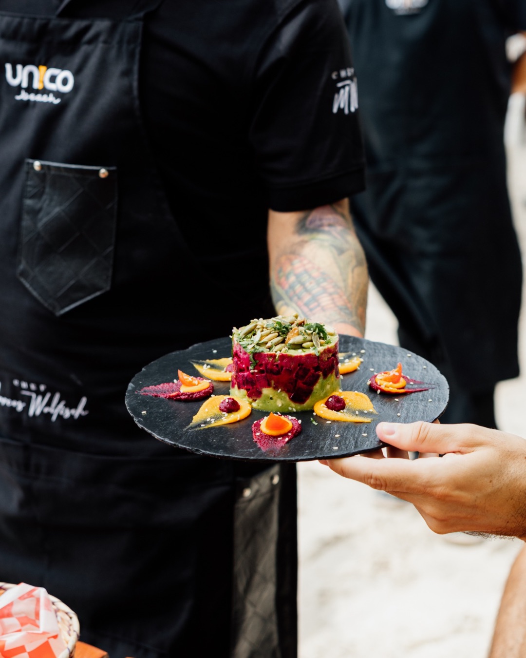 Chef Marcos Walfisch holding a plate of his delicious beet guacamole at Unico Beach Club.